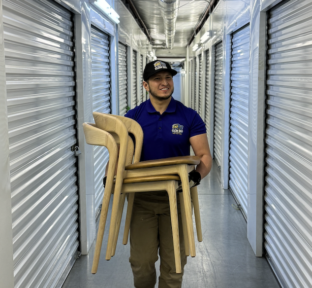 CleanBroServices team member carrying chairs through a storage hallway