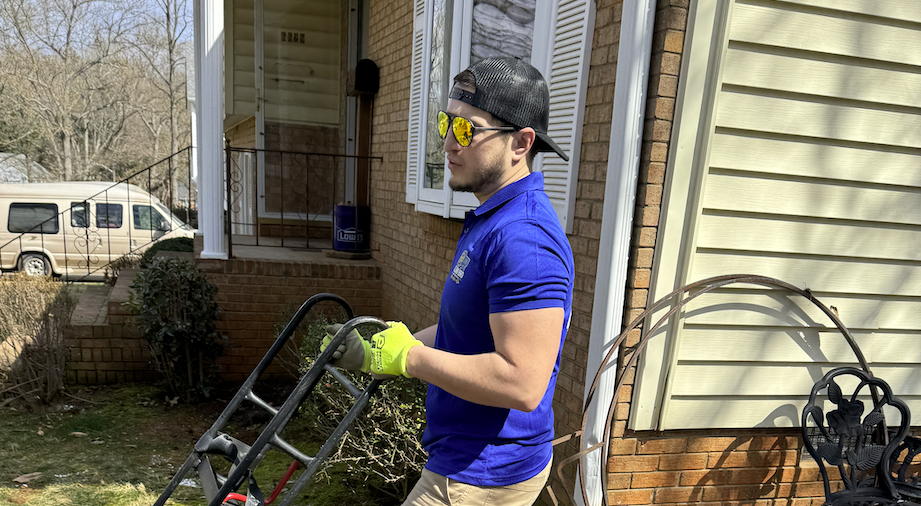 CleanBroServices team member preparing outdoor cleanup equipment beside a home